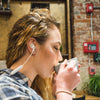 Tyttö, jolla on valkoiset JBuds Pro Bluetooth Signature -kuulokkeet
